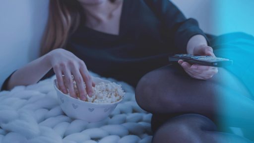 Cozy evening scene with woman enjoying popcorn and watching TV.
