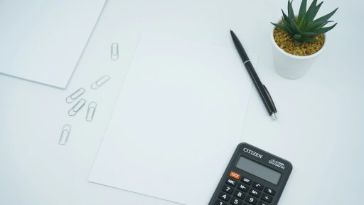 black calculator beside black pen on white printer paper