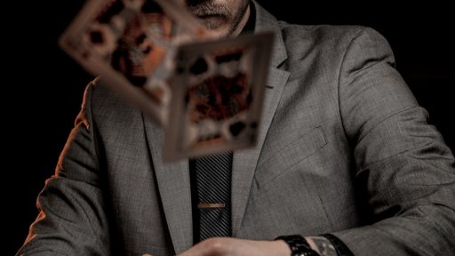 man in gray suit jacket holding jack of diamonds playing card