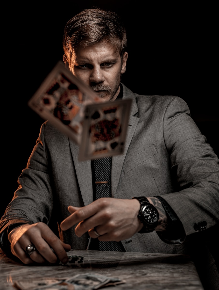 man in gray suit jacket holding jack of diamonds playing card