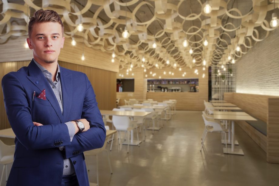 Een restauranthouder die kosten doorrekent achter de bar met papieren en een rekenmachine