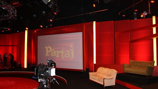 Een tv-presentatrice staat voor de camera in een televisiestudio