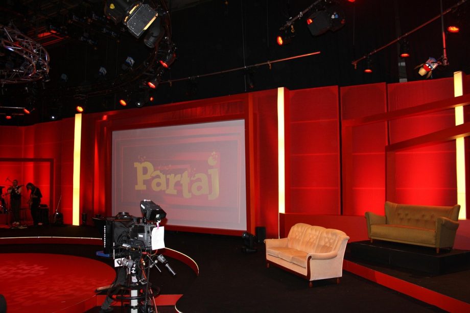 Een tv-presentatrice staat voor de camera in een televisiestudio
