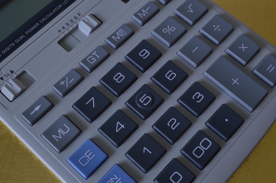 Zzp'er die thuis zijn financiën berekent met pen en papier aan een bureau