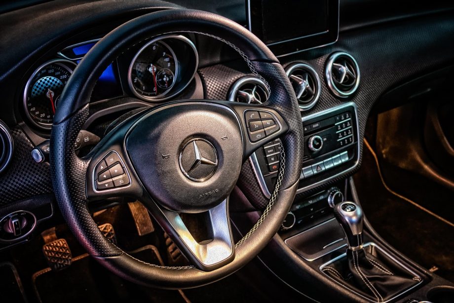 Dashboard van een auto met een rekenmachine op de voorgrond, symbool voor het berekenen van autokosten