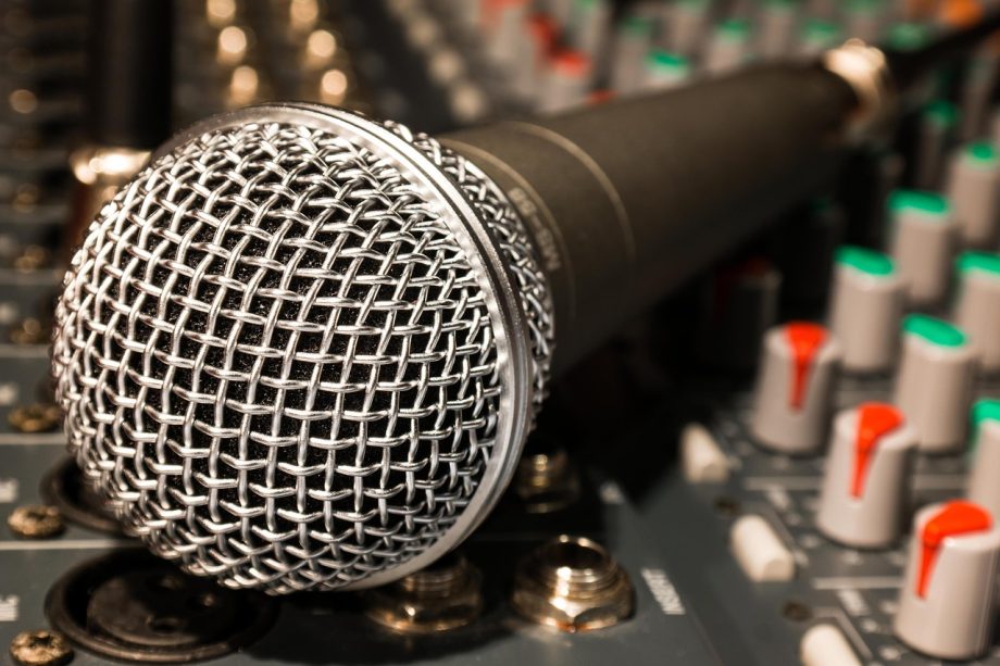 Presentator met microfoon in een tv-studio, symbool voor inkomsten uit televisie en entertainment
